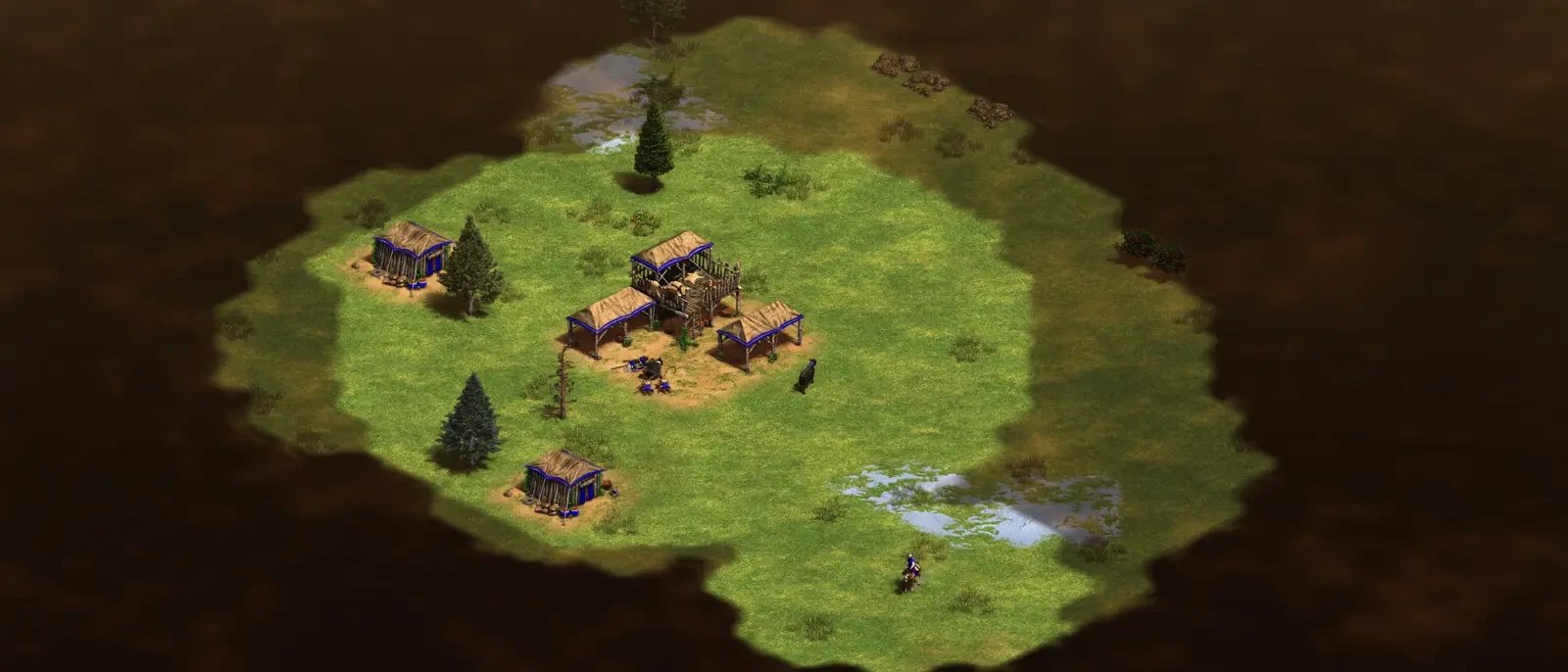 Age of Empires: a Dark Age village of thatched huts on a small patch of explored map, surrounded by unexplored darkness